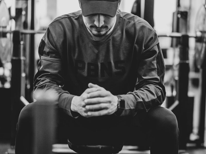man in black jacket and knit cap sitting on bench